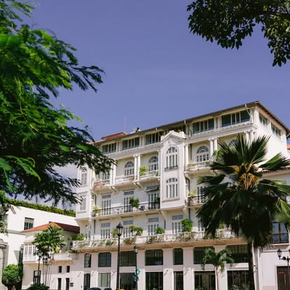 Grand white colonial-style destination building framed by palm trees under a blue sky