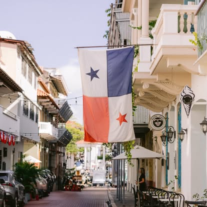 Panama flag hanging across a historic street in Casco Viejo with colonial buildings and outdoor café